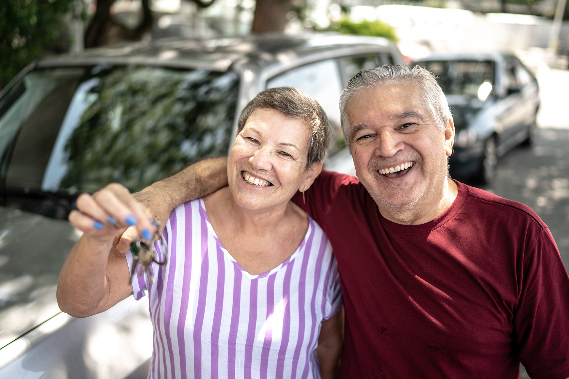 A happy couple in front of their car